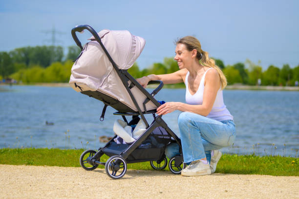 istock Mother Adjusting Baby Stroller by the Lake 2160965997