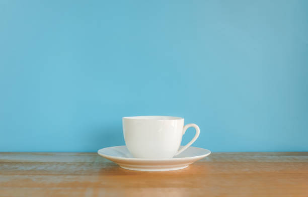 istock White coffee cup on wooden desk with blue background 2160969115