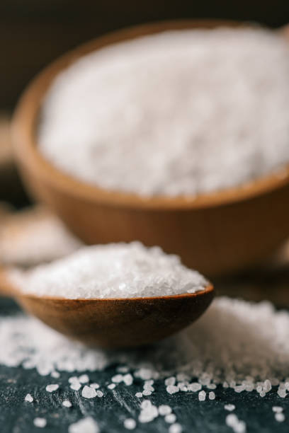 istock Pour salt into a wooden spoon, close-up 2160973539