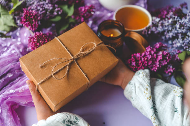 Gift box with a bow in hands in a homely atmosphere