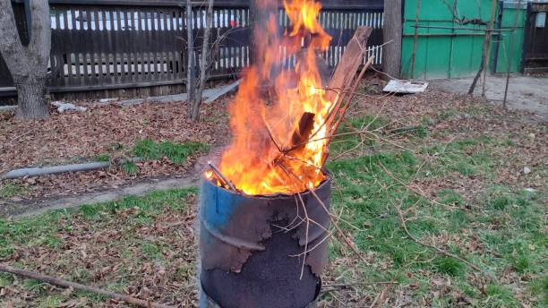 istock Branches and debris burn in the barrel. House yard cleaning. 2160977052