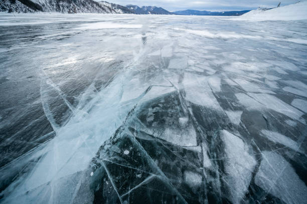 istock Frozen lake with cracked ice patterns and snowy mountain background creates a stunning winter scene 2160978582