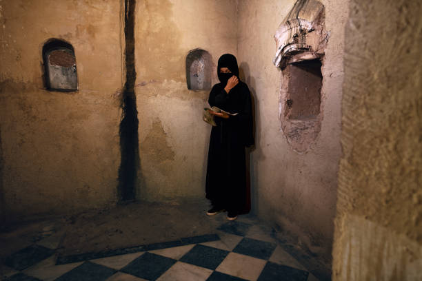 Young woman wearing a burqa inside a shrine reading a religious sacred text
