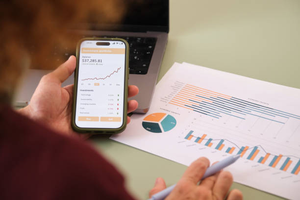 istock Businessman analyzing investment portfolio on smartphone with growing chart 2160981257
