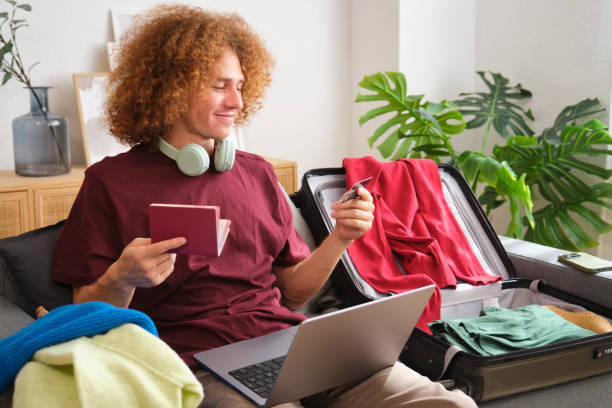 Happy young man booking vacation using laptop and credit card