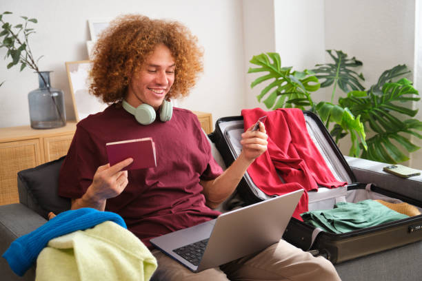 istock Young man booking vacation using laptop and credit card 2160983572