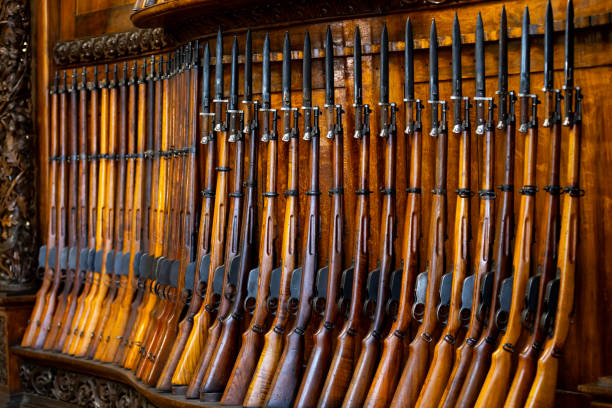 Multiple rows of assault rifles stored on metal racks inside an armory. The scene conveys an atmosphere of increasing militarization and the growing presence of weaponry in contemporary society, fitting themes of global security, defense trends, or analysis of geopolitical tension.