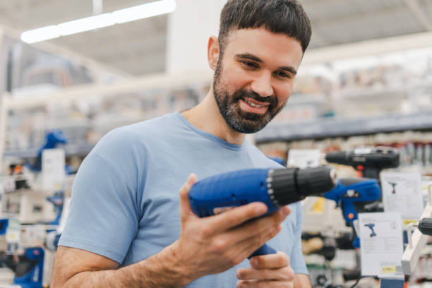 istock Happy young male constructor choosing electric screwdriver, diy, standing in construction store 2160987078