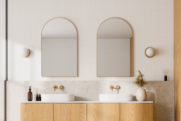 istock Modern bathroom with wooden cabinets, dual sinks, and arched mirrors, light background. Contemporary home or hotel concept. 3D Rendering 2160988140