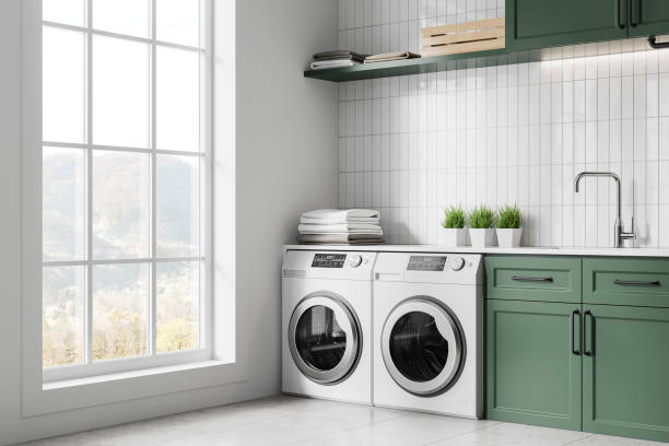 istock White and green home laundry interior with washing machines and sink, window 2160988626