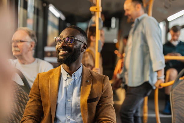 Man smiling on a bus during a full bus ride at rush hour