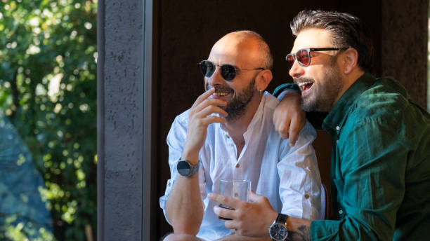 Two middle-aged businessmen in office attire are enjoying their time together at a café outside the office