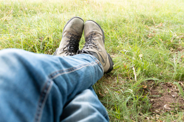 Hiker seen crossing his legs while resting on a long forest hike. The hiker is relaxing part way on a long hike in a wilderness area.