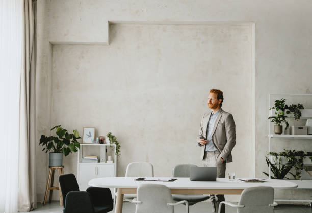 Businessman in Modern Office Looking Out the Window