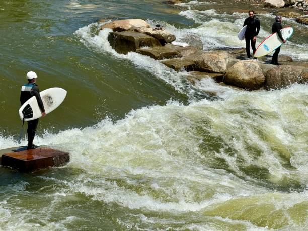 Silhouette of river surfer challenges raging green and white rapids on Eisbach River in middle of European city September 11, 2017 Munich Germany