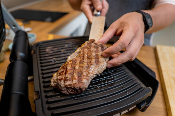 istock Chef at the kitchen preparing beef steaks on the home electric grill 2160997067