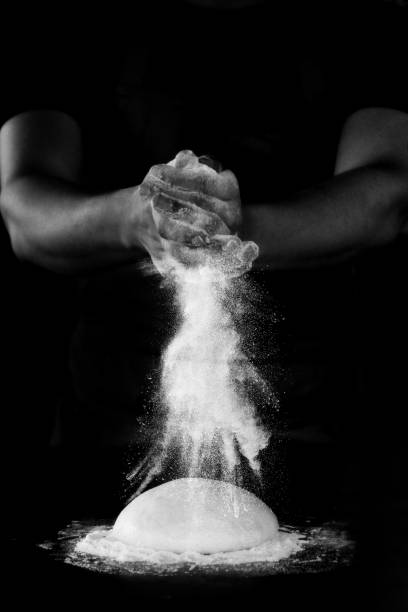 Pizza maker sprinkling flour on pizza dough
