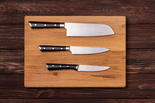 istock Three kitchen knives laying on a cutting board. Top View. 2161002589