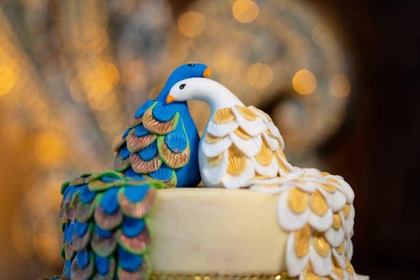 Wedding cake decorated with a pair of handmade icing sugar peacocks.
