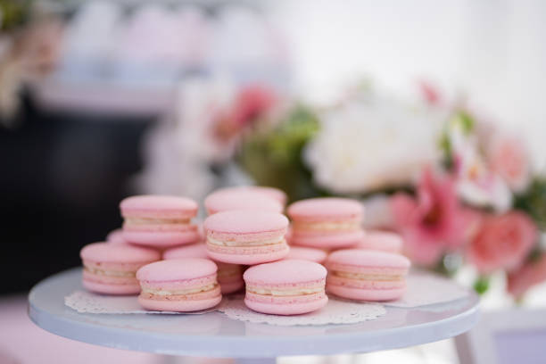 Pink macaroons stacked on a white plate.