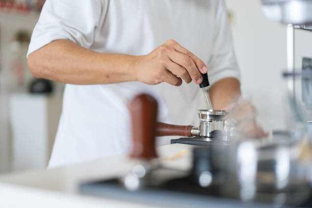 istock Man’s hand using a coffee stirrer to level coffee grounds in a portafilter. 2161006966