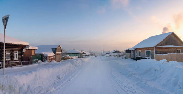 Winter road through a snow-covered village, severe frost, snow haze. Winter village of Cherdyn. Perm Region, Russia. Panoramic view.