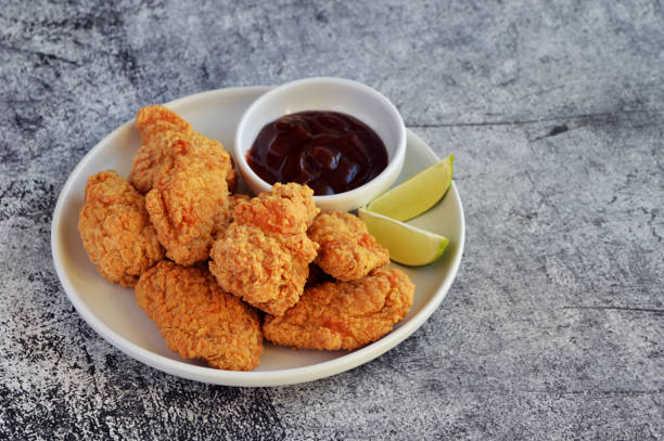 istock Crispy fried chicken served with BBQ sauce and lime wedges on the side in rustic background 2161021100