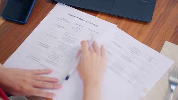 istock Asian financial advisor checking the details in the documents about retirement planning worksheets for her family to secure retired life, young adult woman examining the finance status before choosing retirement plans 2161021113