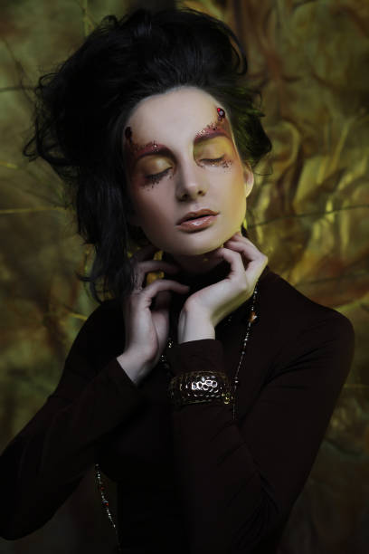 Golden body paint on beautiful woman meditating in front of black background