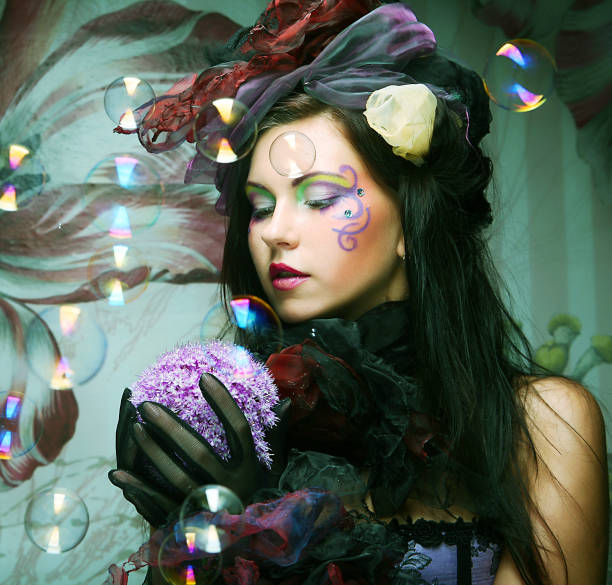 istock fashion model with creative make-up blowing soap bubbles. 2161032087