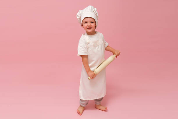istock A smiling child with rolling pin, dressed as a professional chef, is captured in a full-length portrait against a red and pink studio background. Kid aged 3 years (three year old boy) 2161033036