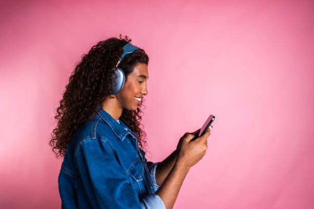 istock Young transgender female listening to music while using smartphone on a studio shot 2161036530