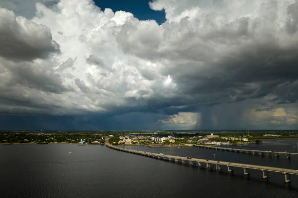 Heavy thunderstorm approaching traffic bridge connecting Punta Gorda and Port Charlotte over Peace River. Bad weather conditions for driving during rainy season in Florida.