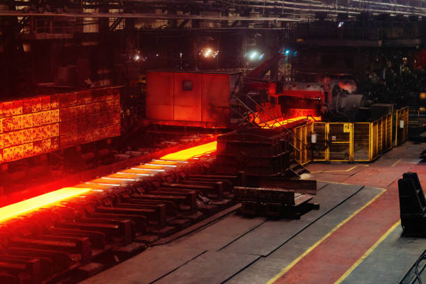 Rolled metal factory hot steel bar on conveyor moving through rollers.