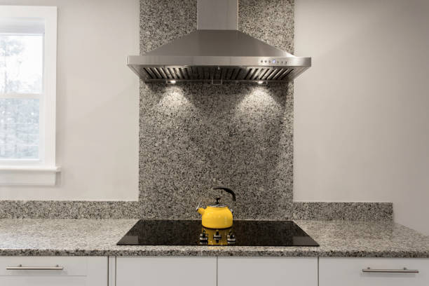 Modern Kitchen With Granite Countertops, Induction Cooktop, And Stainless Hood