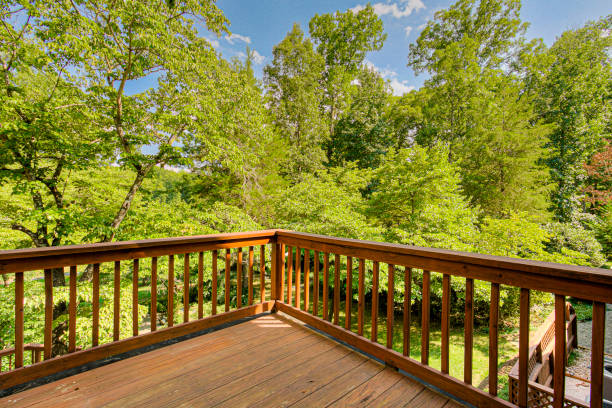 istock Sunlit Wooden Deck With Distinctive Wooden Railings Overlooks Lush Greenery 2161040962