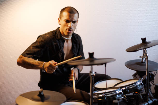 Focused multiracial performer playing drums in music studio Focused mixed race performer playing drums in music studio drummer stock pictures, royalty-free photos & images