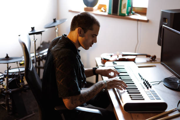 istock Musician playing synthesizer near computer and music instruments in studio 2161051913