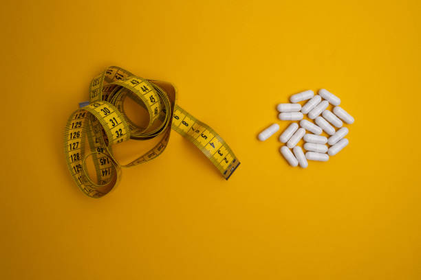 istock Measuring tape and tablets, vitamins on a colored background with space for text. Concept of losing weight, dieting, burning fat, healthy eating 2161054338