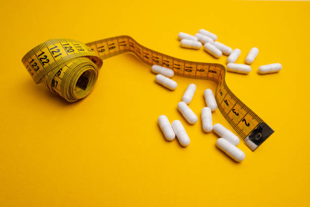istock Measuring tape and tablets, vitamins on a colored background with space for text. Concept of losing weight, dieting, burning fat, healthy eating 2161054339