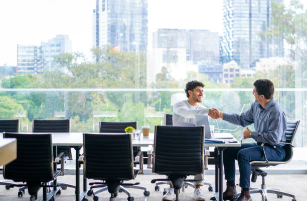 istock Handshake between Two businessmen working on a digital tablet and laptop computer in the office a board room or meeting room. 2161058369