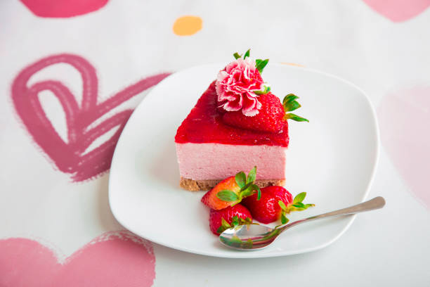 Strawberry cheesecake decorated with fruit and flowers over a hearted backround