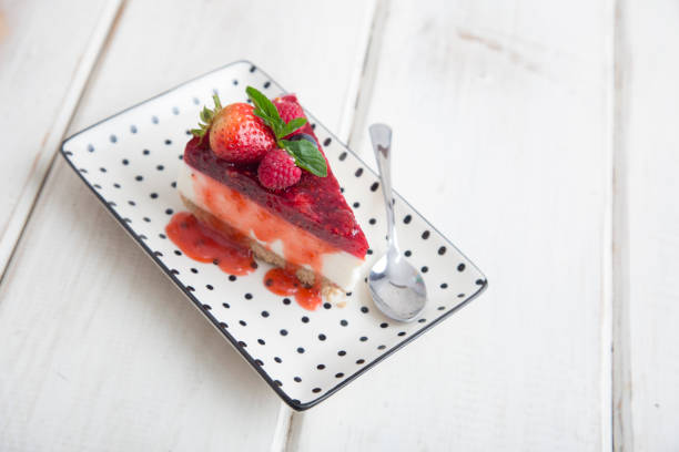 Strawberry chessecake with fresh fruit topping on a white wood background