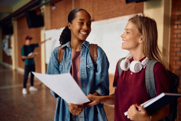 istock Happy black high school student and her classmate looking at test results in a hallway. 2161063795