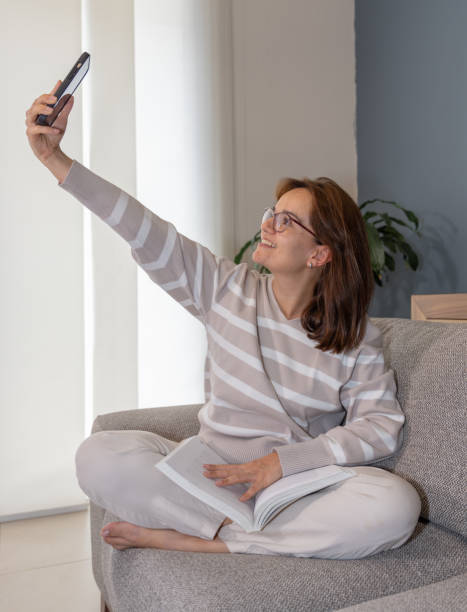 istock Woman sitting on a sofa taking a selfie with her phone 2161064238