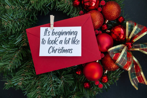 istock IT'S BEGINNING TO LOOK A LOT LIKE CHRISTMAS text on postcard with red envelope on handmade Christmas wreath. Zero waste eco-friendly Christmas. Sustainable greeting card 2161065458