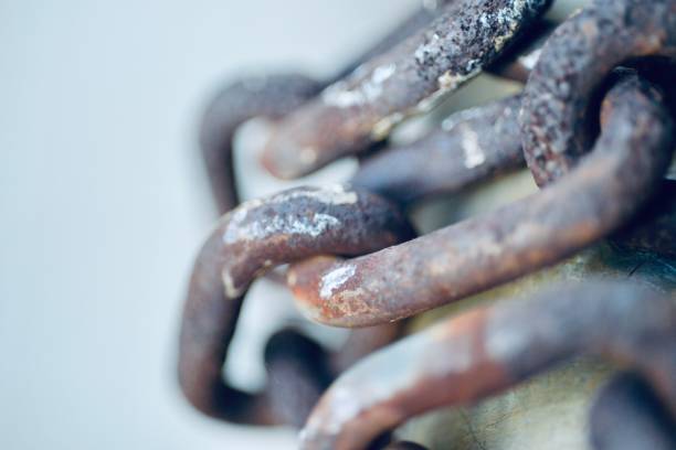 A close-up photograph of a rusty chain wrapped around a metallic object. The image focuses on the texture and corrosion of the chain links, with a blurred background that emphasizes the details of the rust and metal