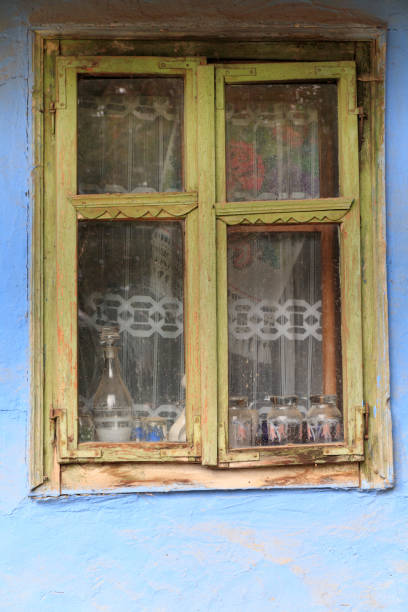 Old wooden window frame on a log house wall. Traditional rural architecture, natural wood texture, rustic and ethnic style background for design concepts.