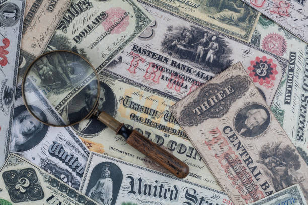 istock Retro US banknotes and silver certificates with silver dollar coins and magnifying glass 2161072046