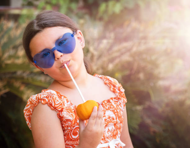 Child drinks tangerine juice in the tropics on vacation